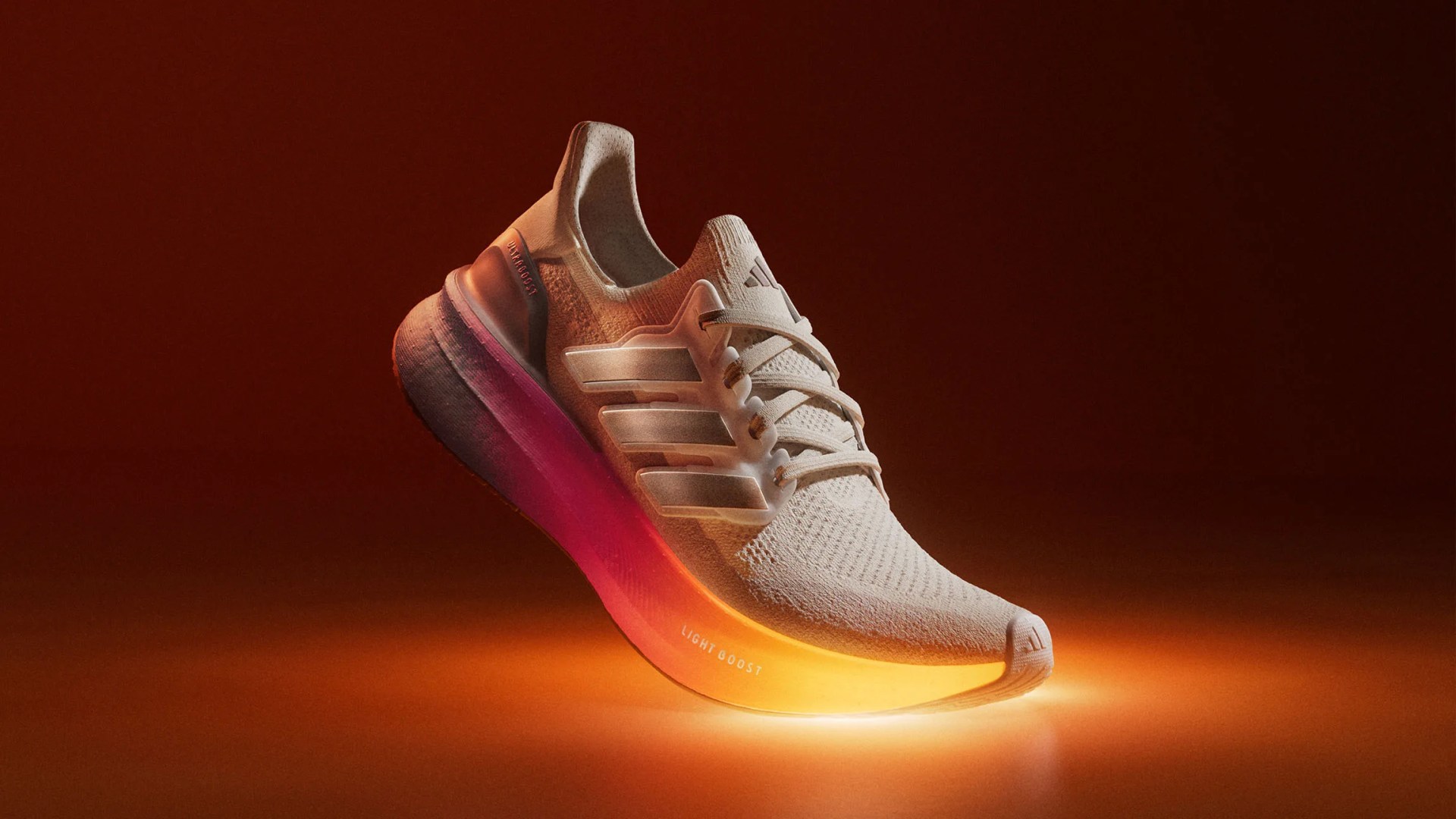 Adidas Ultraboost 5 sneaker floating in air with toe touching an orange surface emitting light at the point of contact