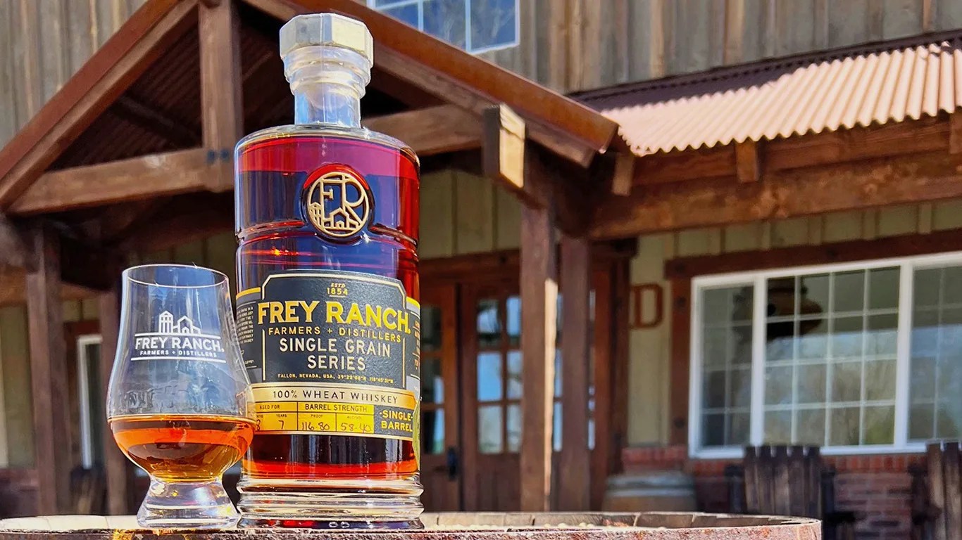 bottle of whiskey next to a glass in front of an old saloon