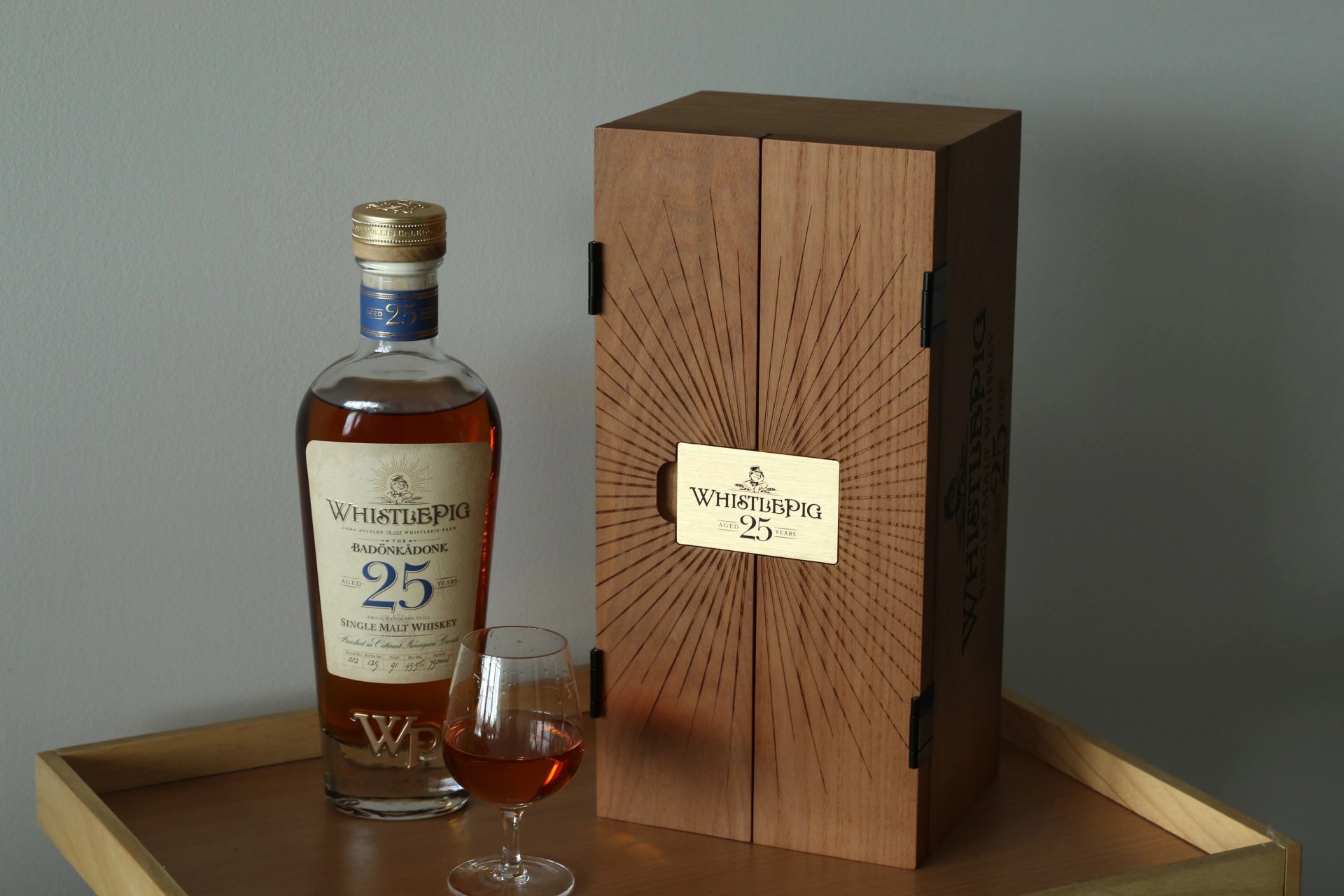 bottle of whistlepig whiskey next to its wooden box and glass