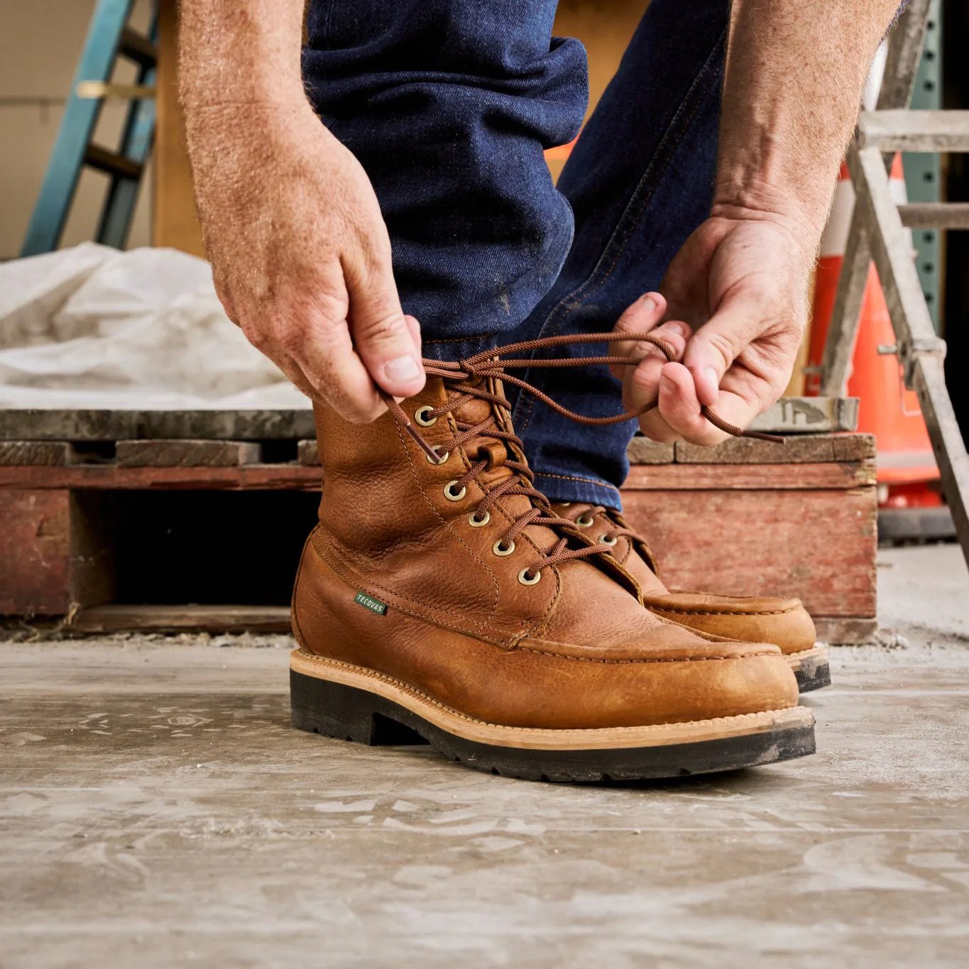 man tying laces of brown boot