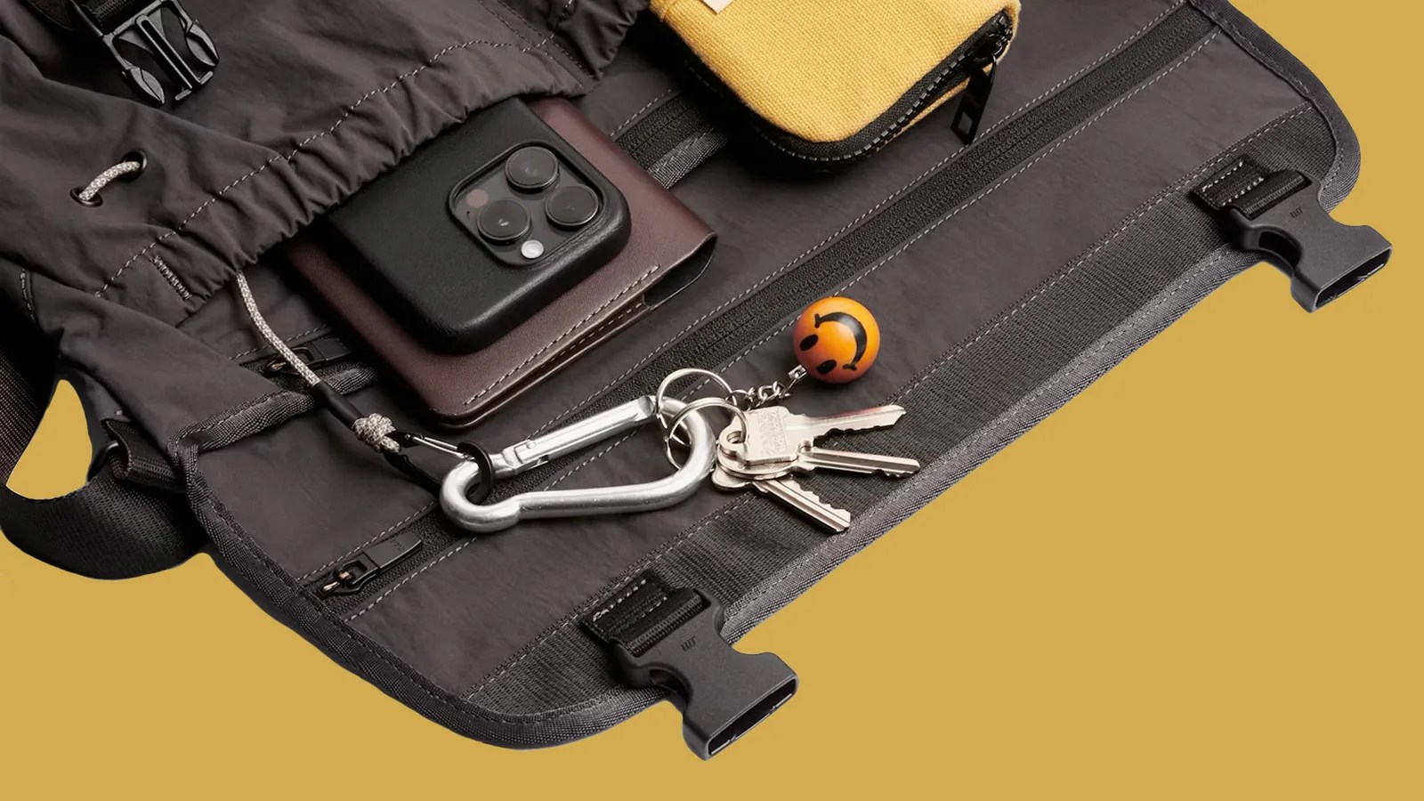 Bellroy's cinch messenger bag shown laid flat and open to reveal its organizational pockets for phones, keys and other small items.