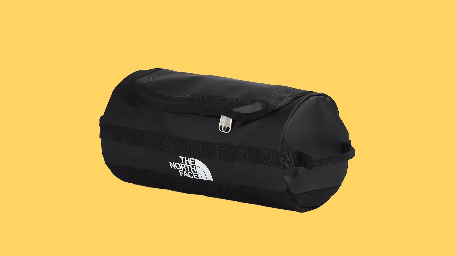 The North Face Base Camp Travel Canister bag in black shown at an angle from the front against a bright yellow background