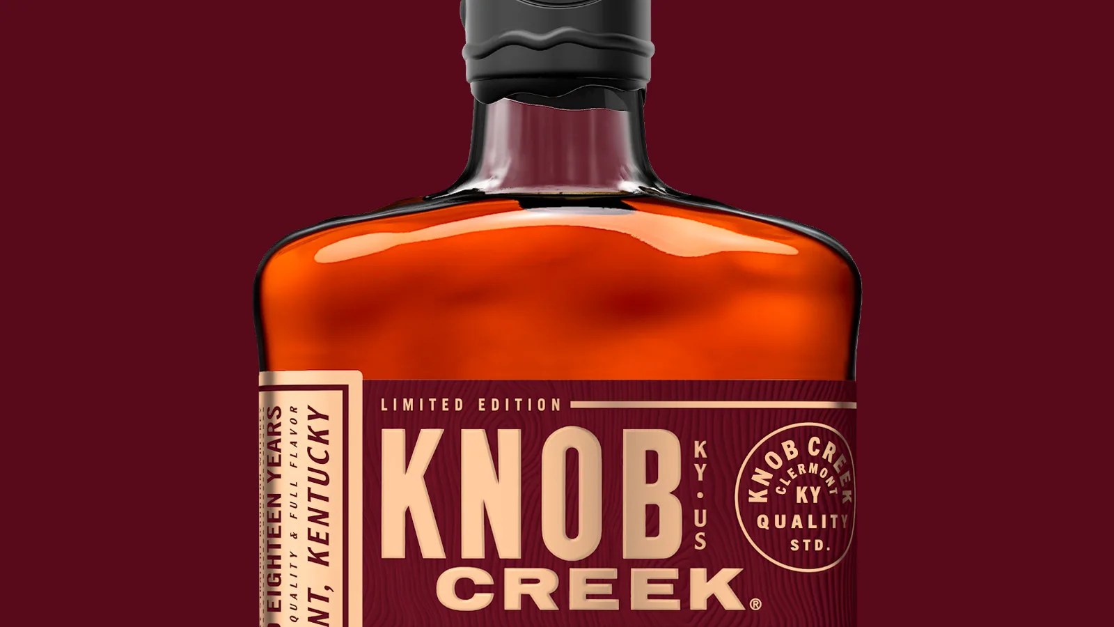 Upper portion of Knob Creek 18 year old bottle down on a red wine colored background