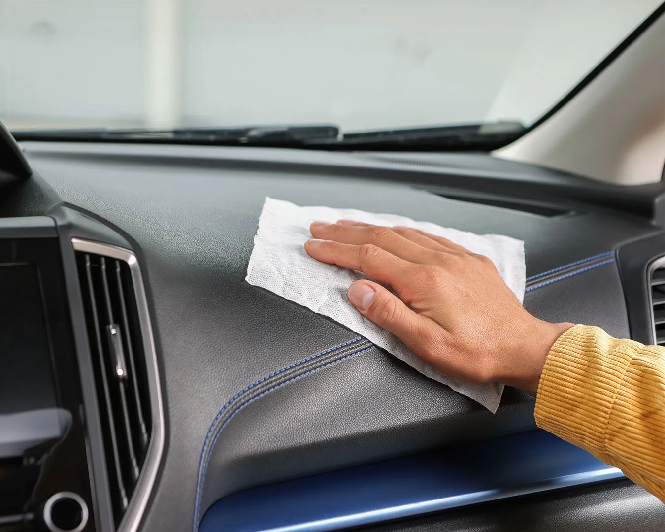 a hand wiping a car dashboard with cloth