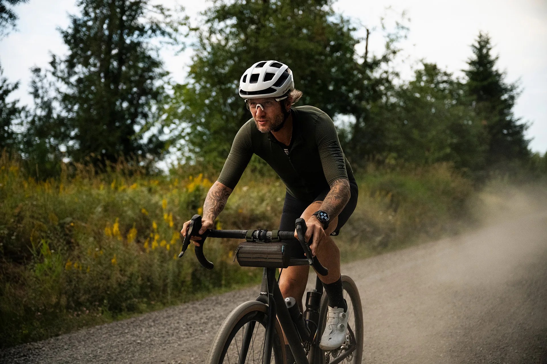 man riding bike with watch on gravel road