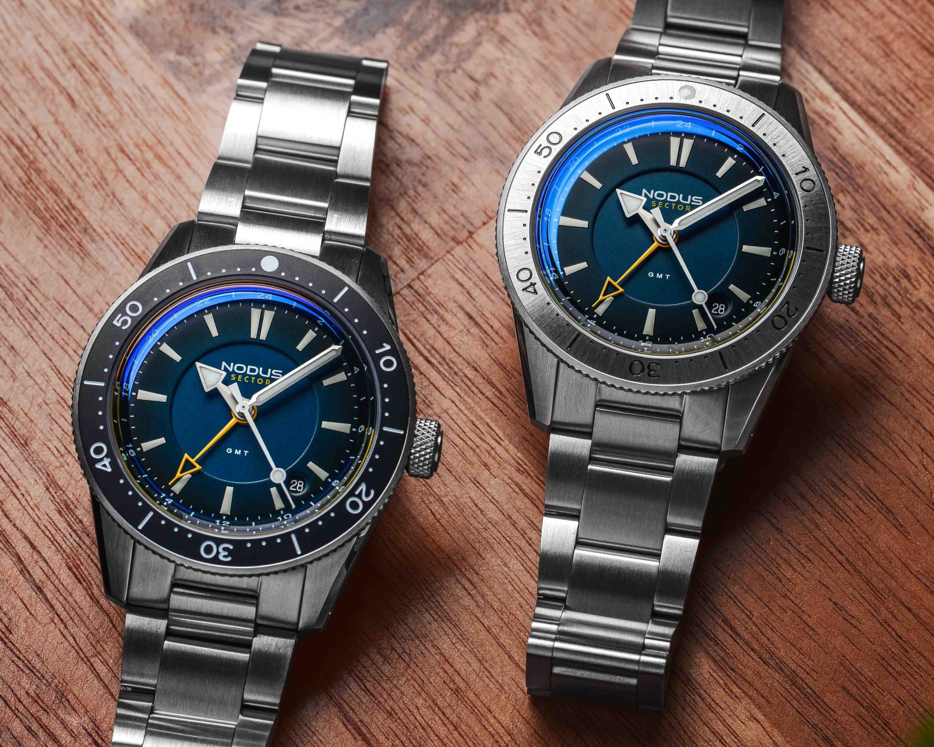 two steel dive watches next to each other on a wood table