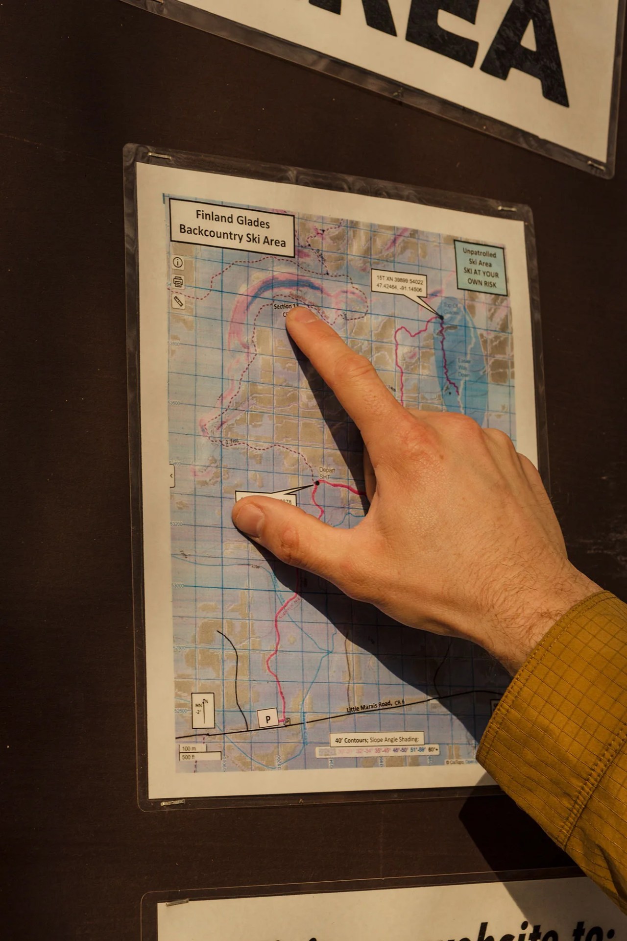 A hand points to a map of the finland glades backcountry ski area